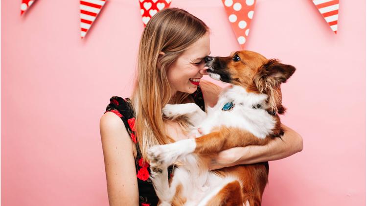 Woman holding and getting kisses from her dog valentine.